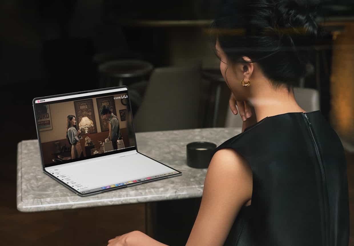 一个女人使用折叠态的 HUAWEI MateBook Fold 非凡大师观看影片，上屏是影片内容，下屏显示视频的评论